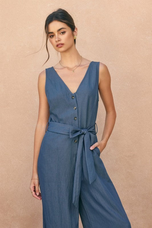 Modelo vistiendo un enterizo Marita Concept azul sin mangas con escote en V, botones frontales y cinturón ajustable.